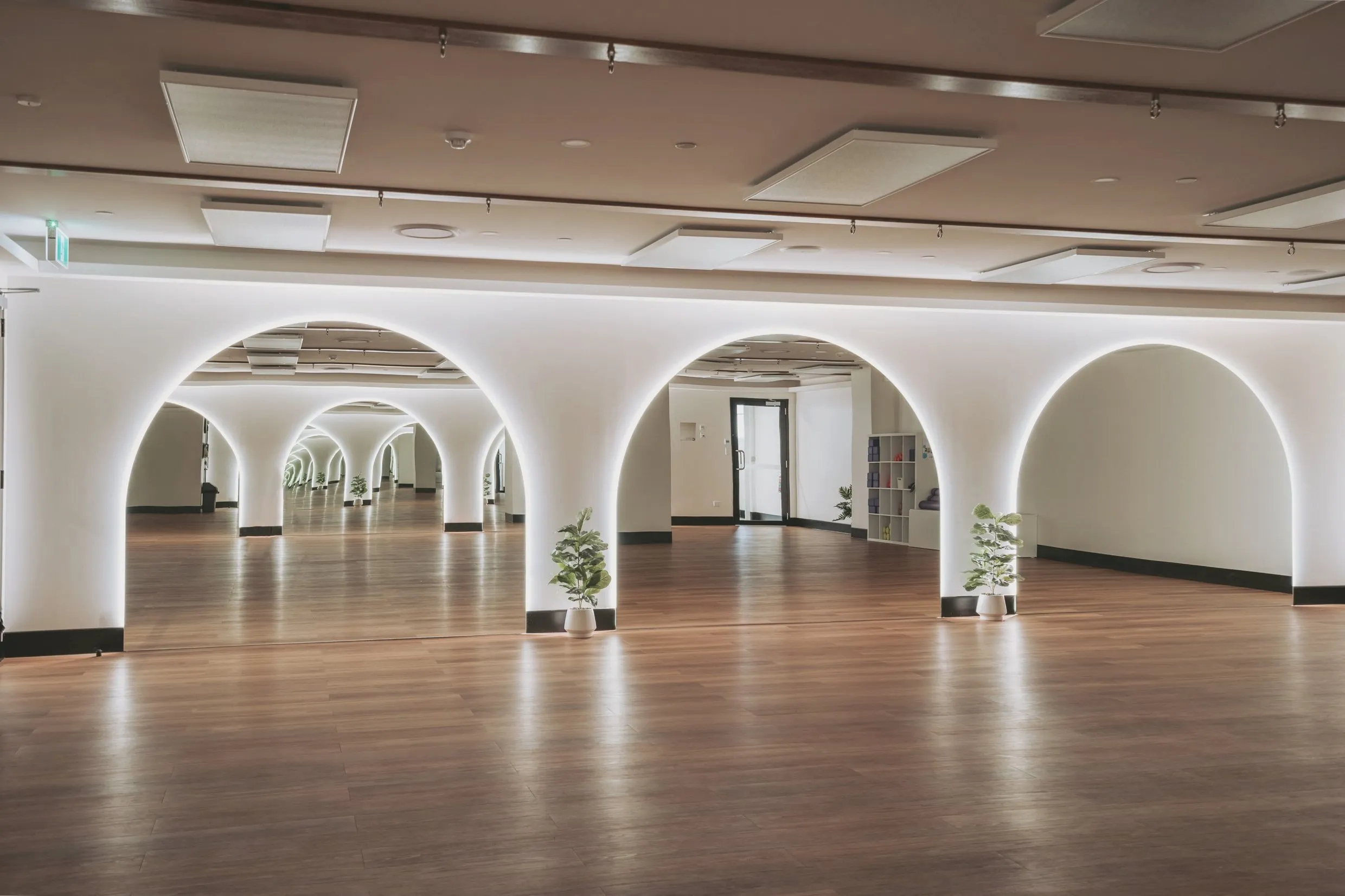 The mind-body studio: backlit arches mirrored down the length of the room, a timber floor, plants and shelves of mats and blocks.