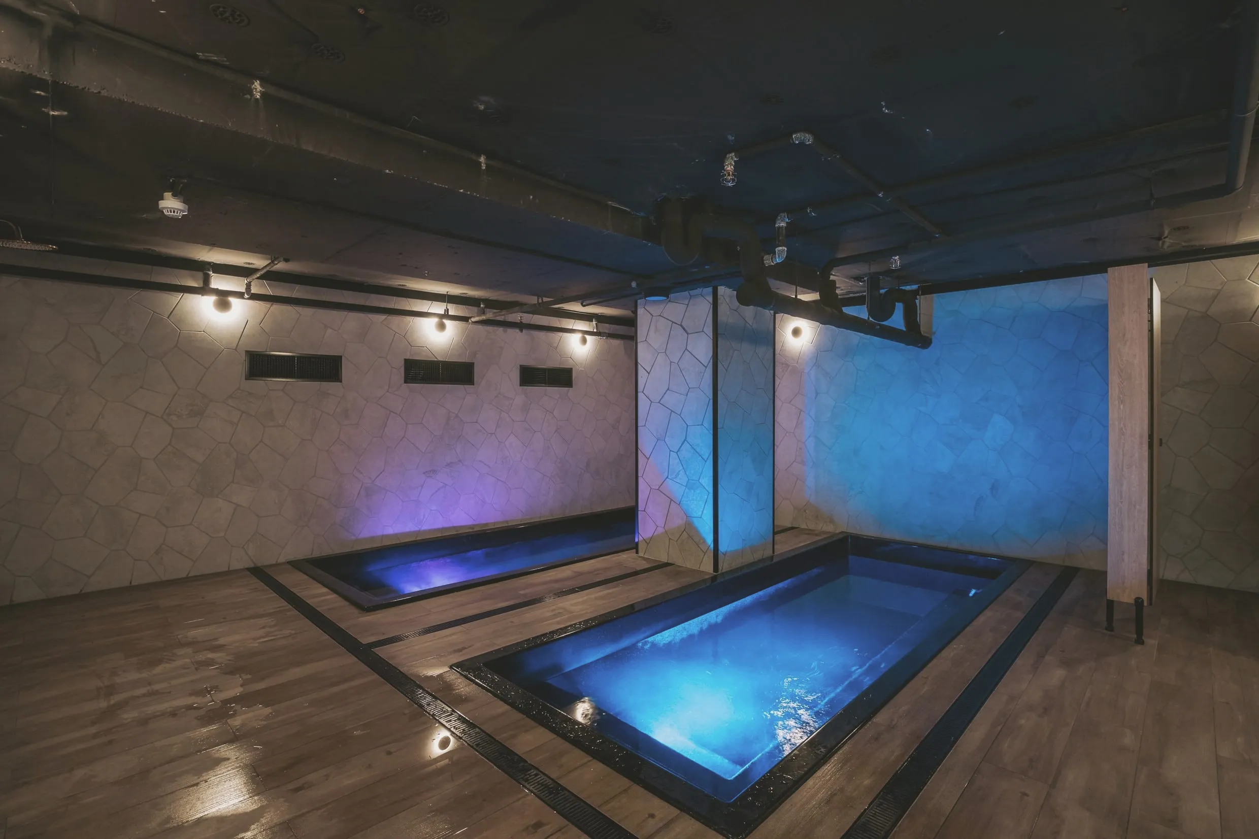 Sunken magnesium recovery pools lit deep blue, set into a timber deck beneath a dark ceiling.