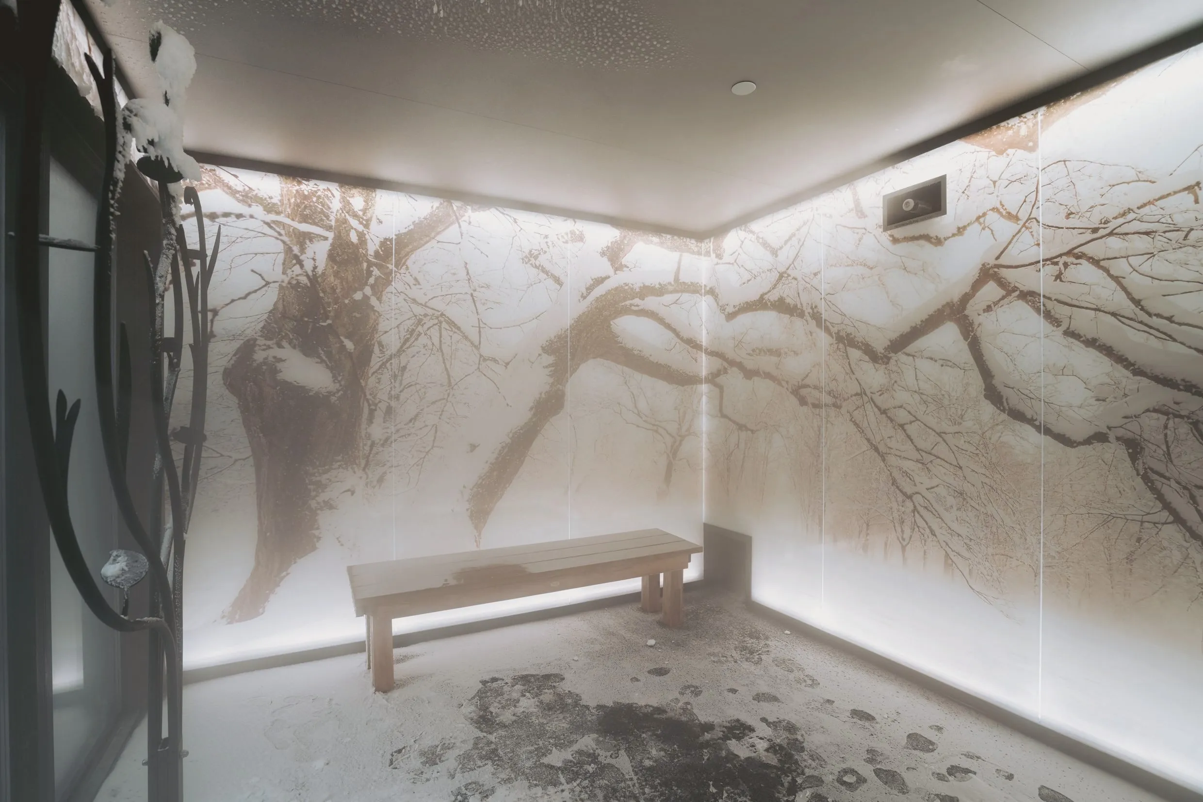 The snow room: real snow underfoot, a snow-covered branch by the door and a backlit winter-forest mural wrapping the walls.